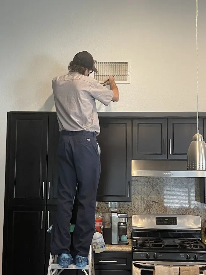 Technician inspecting an air vent during HVAC service in Moundsville
